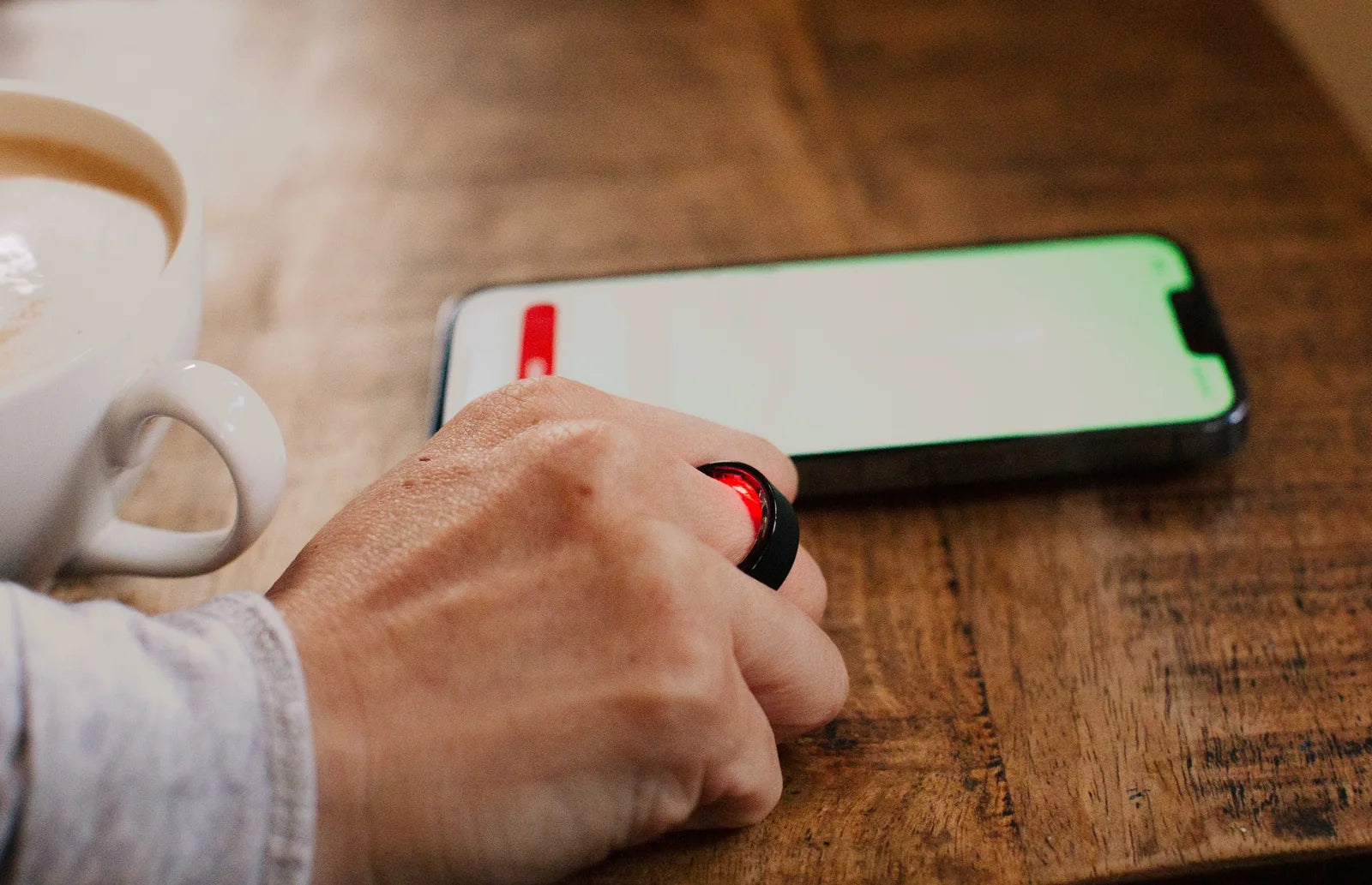 A person wearing a ring while using a phone over coffee