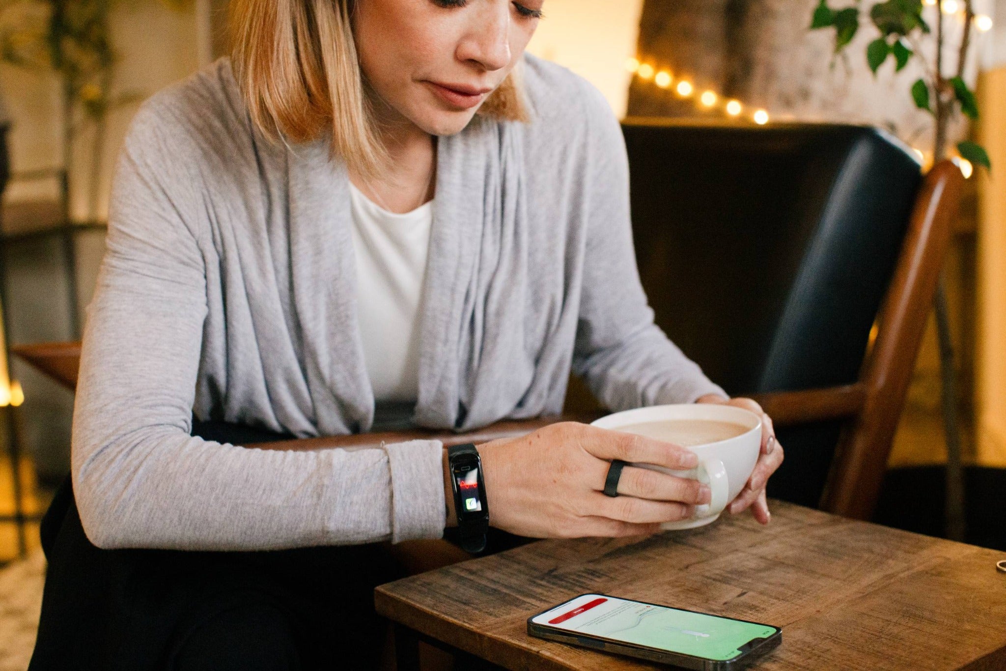 A woman taking a break with a cup, phone, ring, and wrist wearable